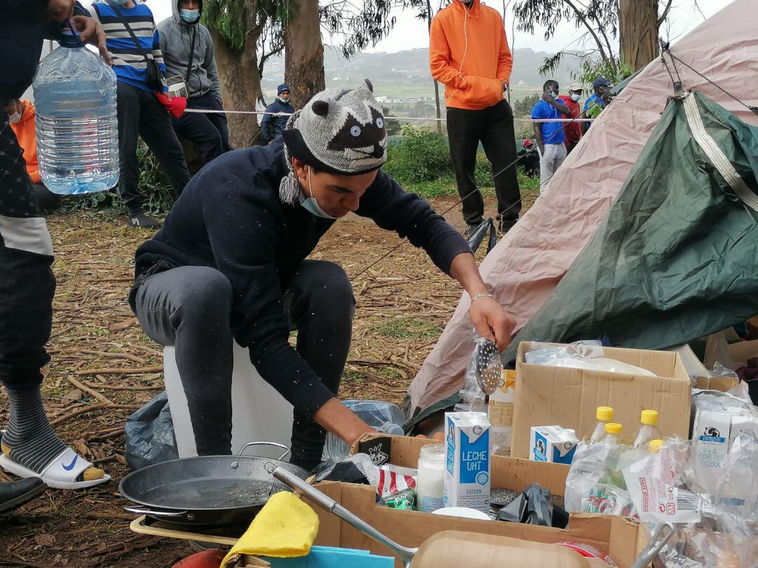 Uno de los 1.500 migrantes acogidos en Las Raíces organiza los alimentos en el campamento organizado en el exterior