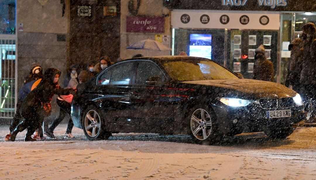 Varias personas empujan un vehículo durante una nevada.