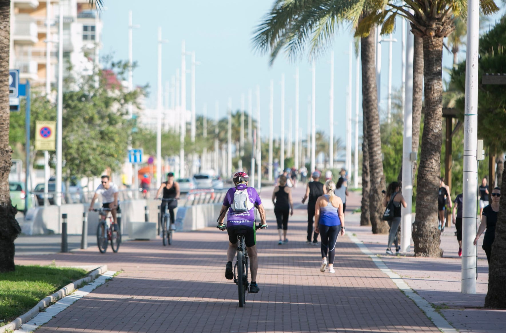 Una mujer se desplaza en bicicleta por la fachada marítima de Gandia