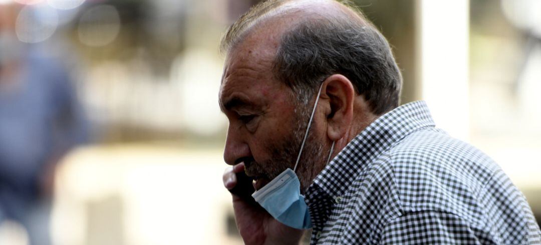 Un hombre con mascarilla habla por teléfono.