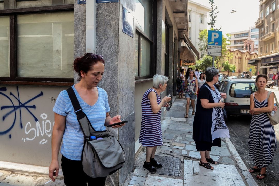 Varias personas esperan junto a un edificio del centro de Atenas tras el terremoto de este viernes.