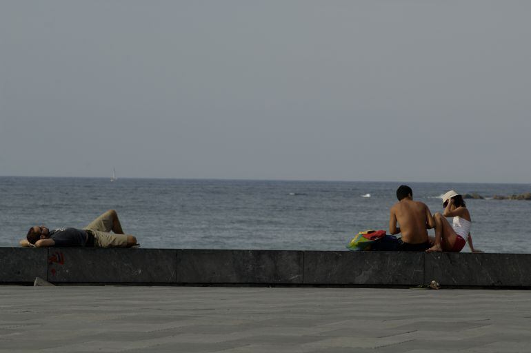 Dos jóvenes charlan en la playa de la Zurriola en una imagen de archivo.