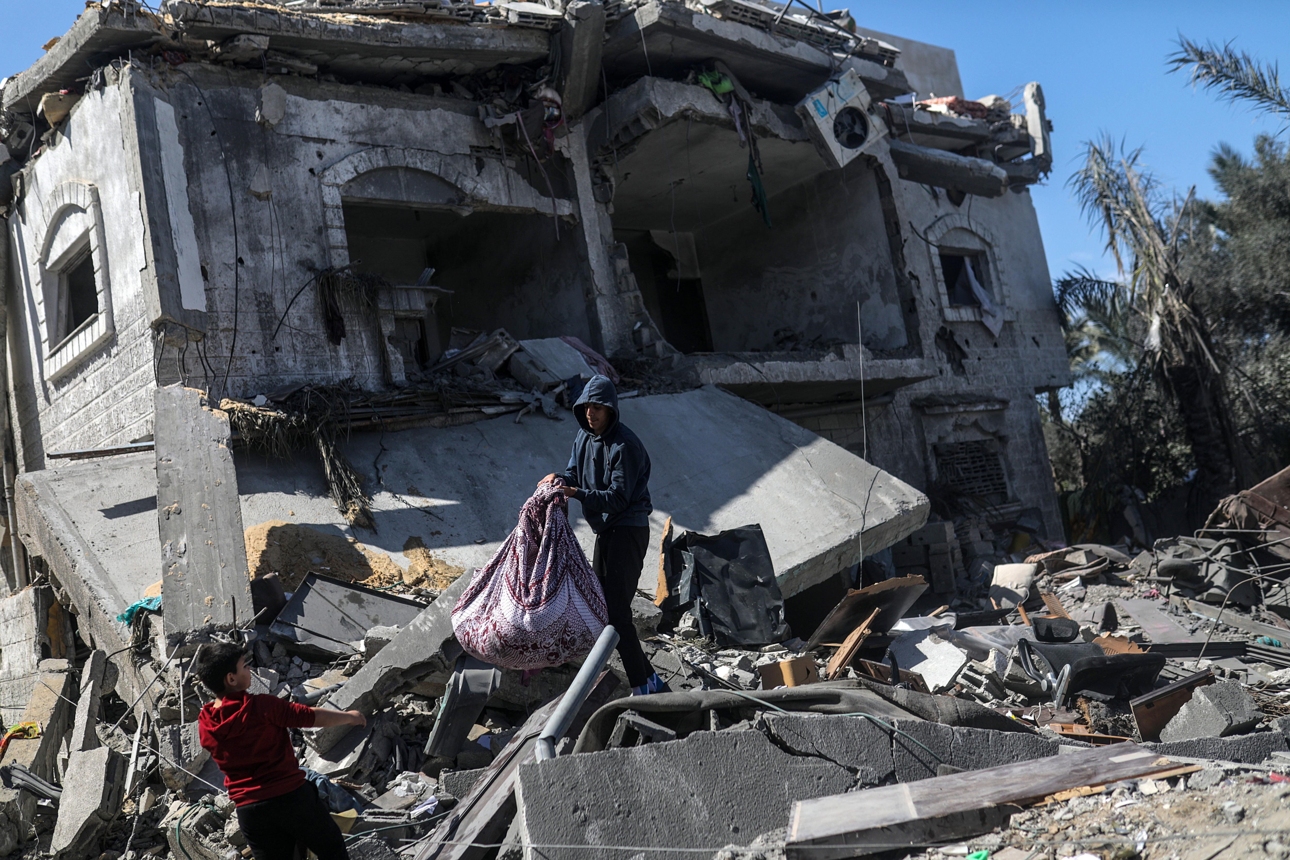 Imagen de varios palestinos en los escombros de un edificio derruido tras un bombardeo israelí en Gaza