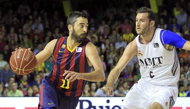 El escolta del FC Barcelona Juan Carlos Navarro avanza con el balón ante la defensa del alero del Real Madrid Rudy Fernández