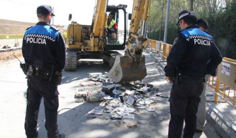 Dos Policías Locales durante la destrucción de material pirata