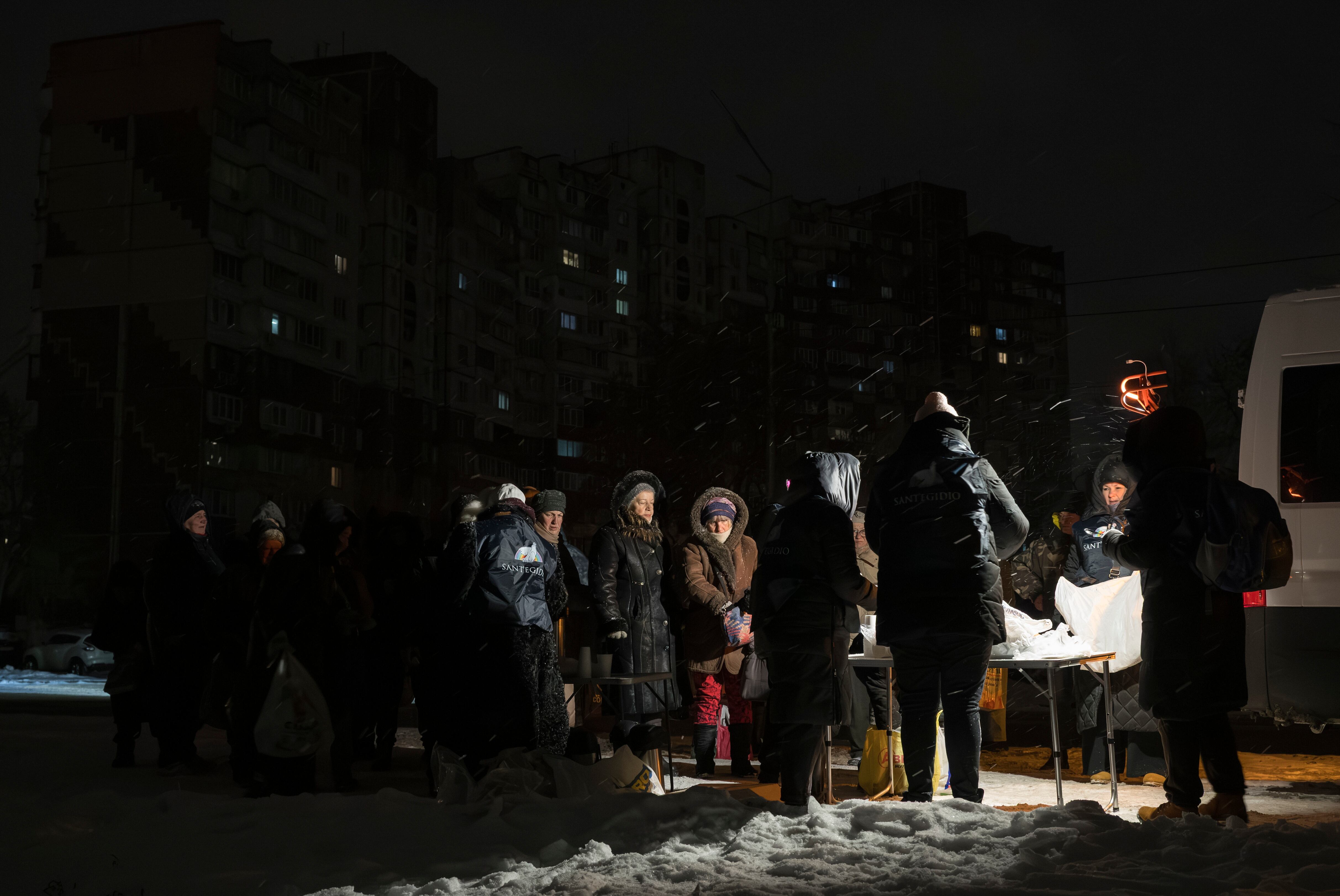 Miembros de una comunidad de vecinos distribuyen comida caliente ante la falta de electricidad.