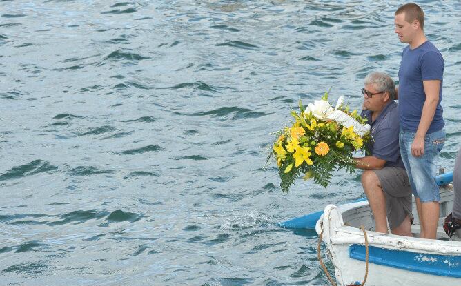 Los pescadores locales en un barco se preparan para lanzar una ofrenda floral en las aguas del puerto de Lampedusa