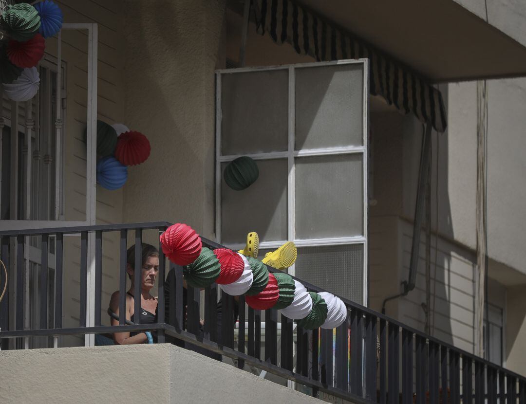 Una vecina del barrio de Los Remedios en su terraza decorada con farolillos tradicionales de la Feria de Abril, suspendida por coronavirus (Covid-19).