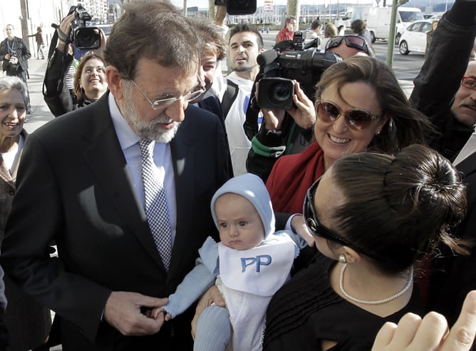 El presidente del PP y candidato a la presidencia del Gobierno, Mariano Rajoy, acompañado por la candidata del partido al Congreso Ana Madrazo (d), conversan con una madre y su hijo mientras daban un paseo por las calles de Santander