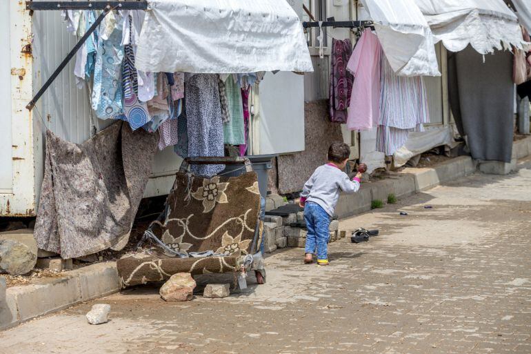 Un niño juega a la entrada de uno de los 3.184 contenedores de 21 metros cuadrados que son el hogar de 15.411 personas en el campo de refugiados de Oncüpinar en el sudeste de Turquía