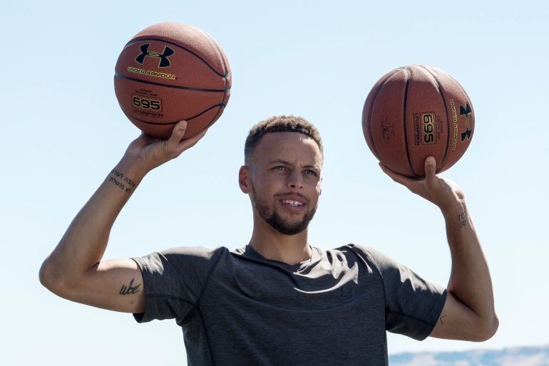 Stehpen Curry posa con dos balones de baloncesto