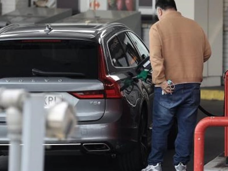 Un hombre repostando en una gasolinera.