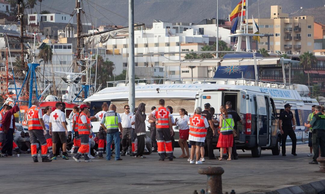 Un grupo de personas migrantes son atendidas y asistidas por personal de la Policía Nacional y Cruz Roja en el Puerto de Los Cristianos, Arona (Tenerife).