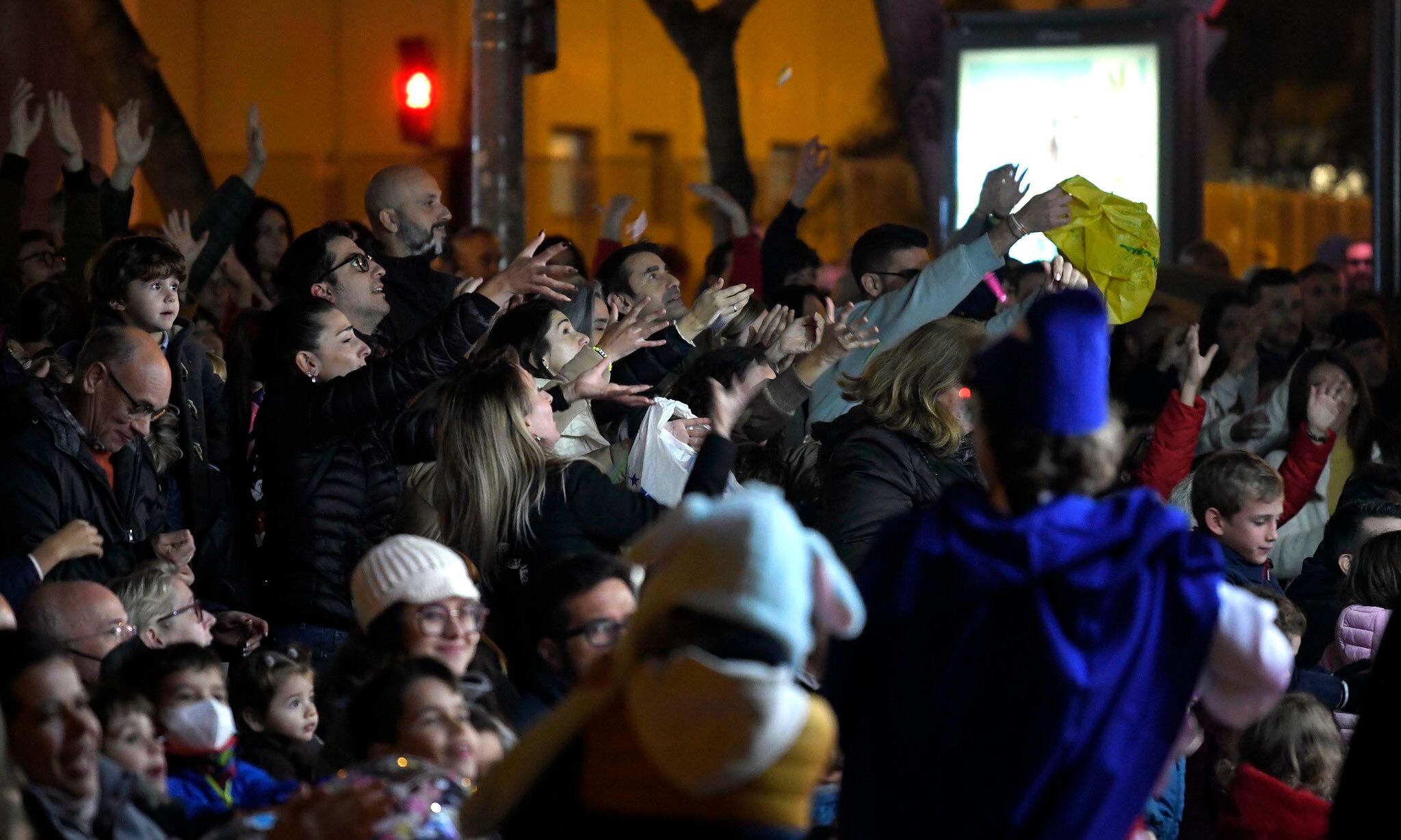 Asistentes a la cabalgata de Murcia extienden sus manos para coger caramelos