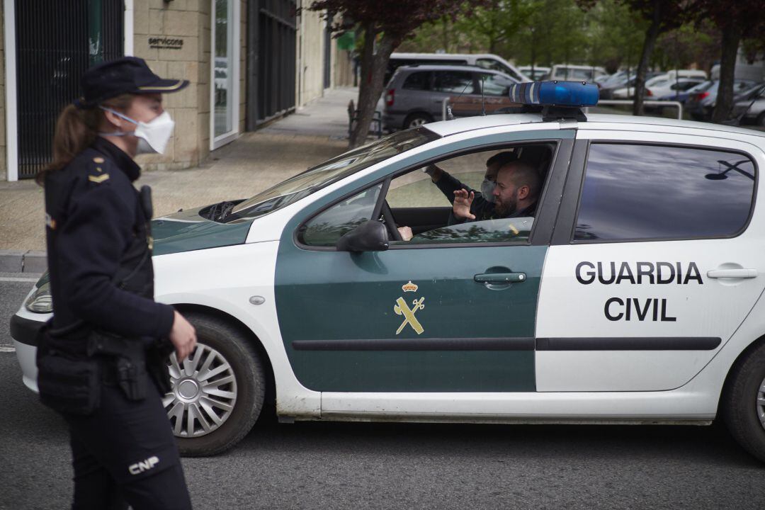 Un vehículo de la Guardia Civil pasa junto a un control de la Policía Nacional