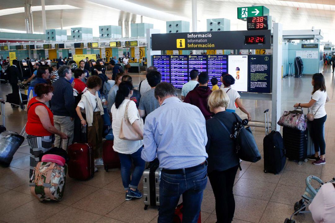 Varios viajeros observan horarios de vuelo en el Aeropuerto de Barcelona