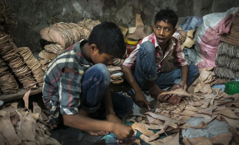 Rakib Mridha (a la derecha) tiene 12 años y trabaja desde los nueve en un taller que fabrica suelas de cuero para zapatos. En Bangladesh está prohibido por ley que los menores de 14 años trabajen; pero además, esta tarea está vetada a los que tienen entre