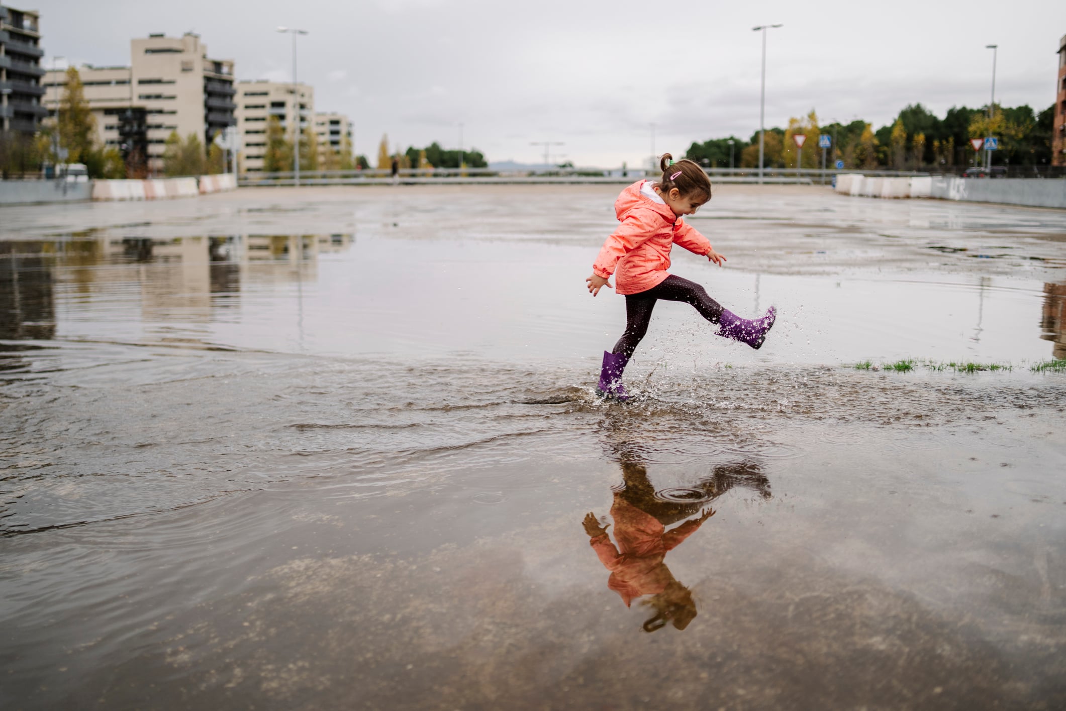 Una niña juega en un charco.