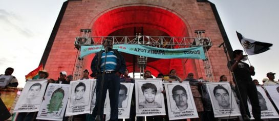 Felipe de la Cruz, the father of one of the 43 missing students from the Isidro Burgos rural teachers college, speaks to a crowd in front of other relatives holding posters of their missing loved ones, during a protest at the Revolution Monument in Mexico