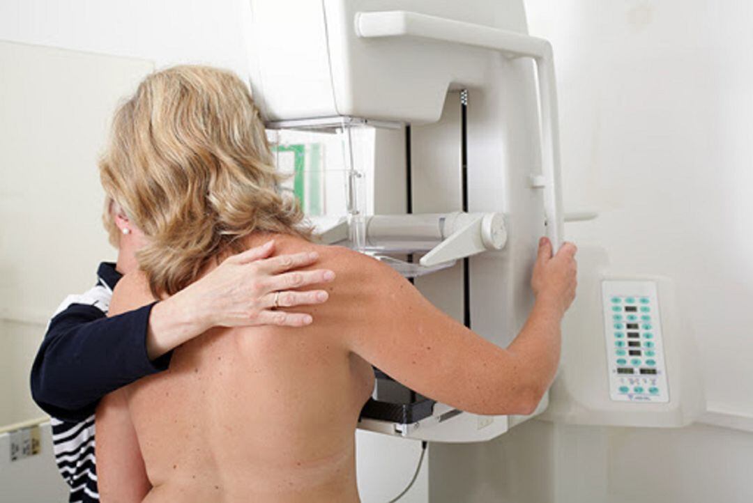 Una mujer realizandose una mamografía.