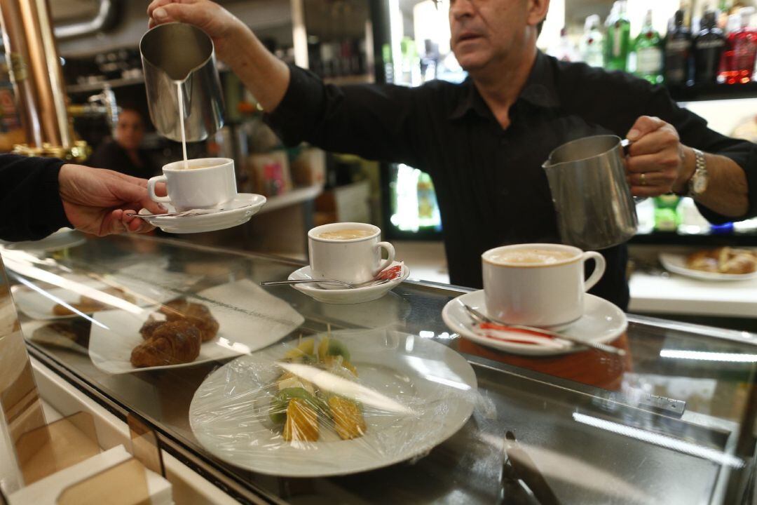 Un camarero sirve tazas de café en una cafetería. 