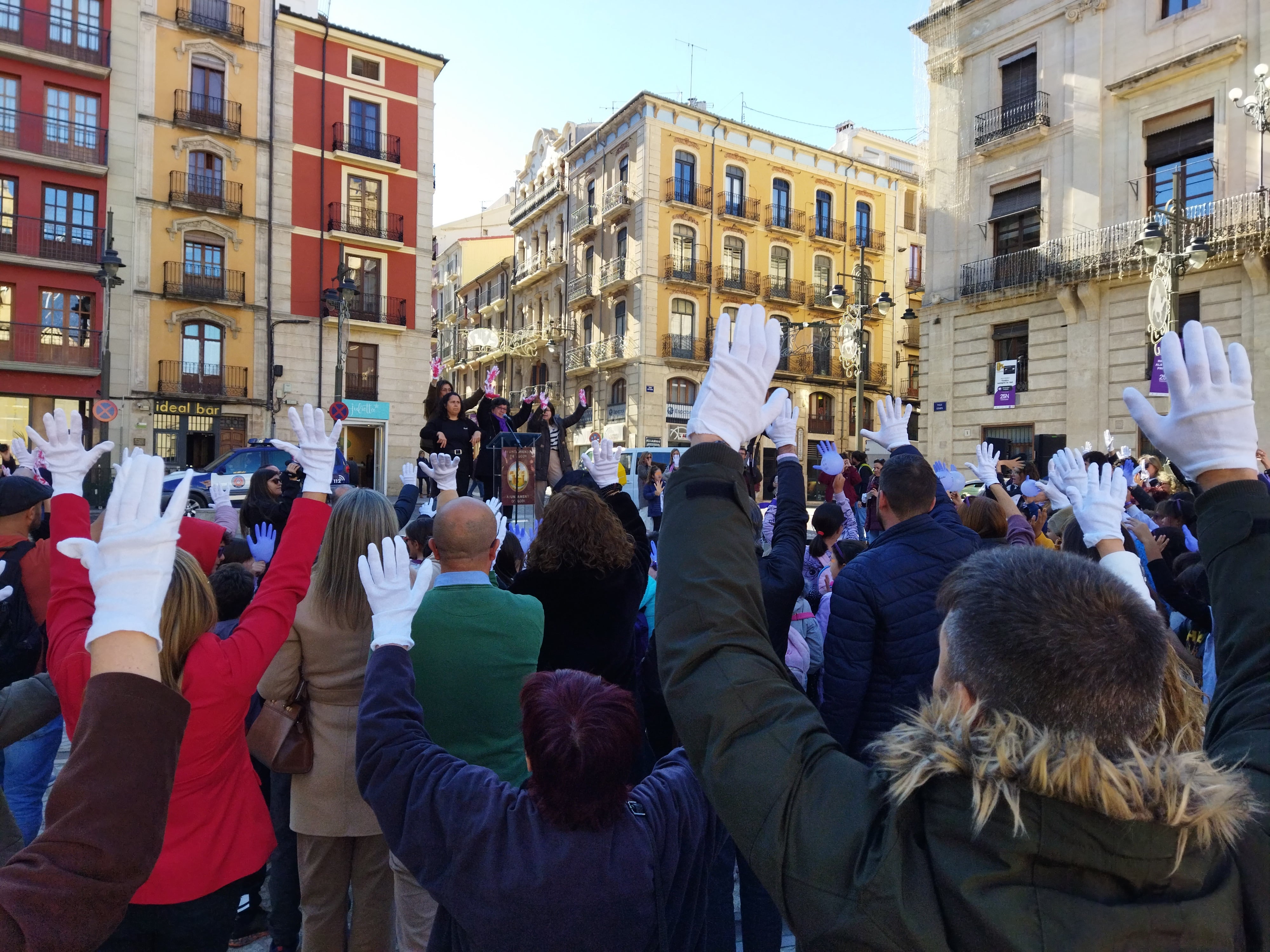 Los asistentes levantando las manos con guantes blancos para decir "basta ya" por la violencia de género.