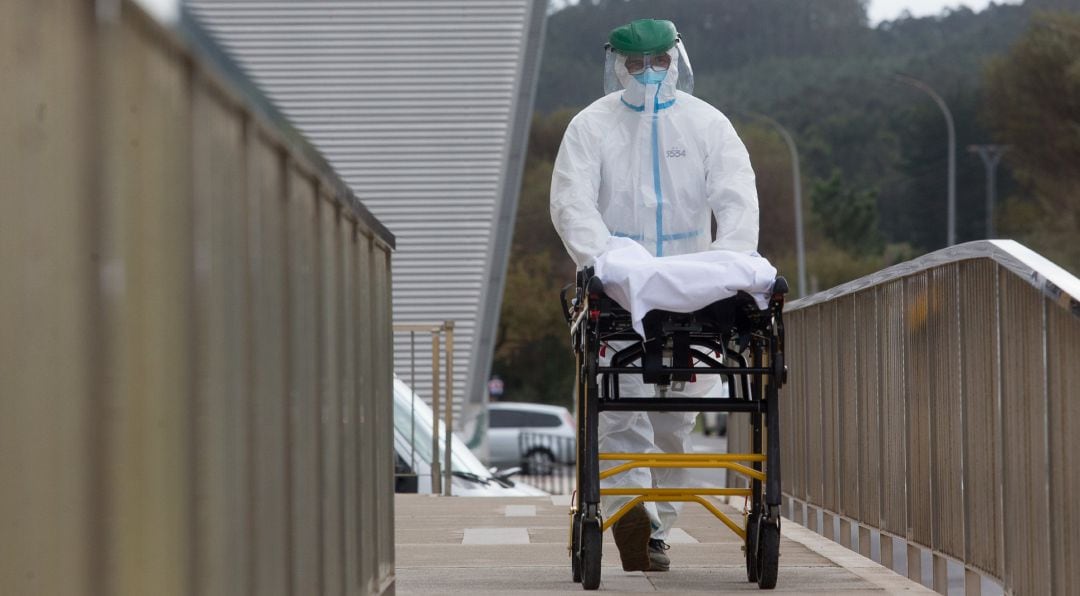 Un trabajador sanitario totalmente protegido traslada una camilla en las inmediaciones de la residencia de ancianos de San Cibrao, en Lugo.