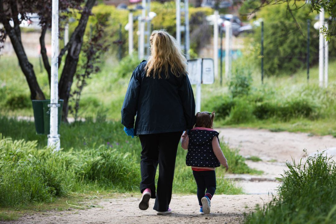 Una madre pasea con su hija por un parque de Madrid