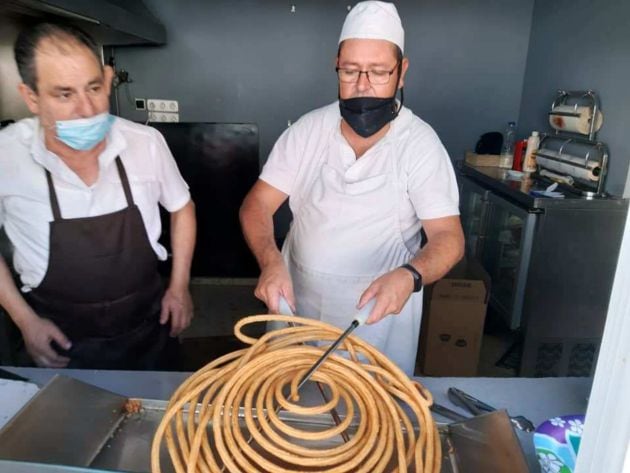 Adrián García portando una rueda de churros junto a un compañero del bar La Parada, en La Plata