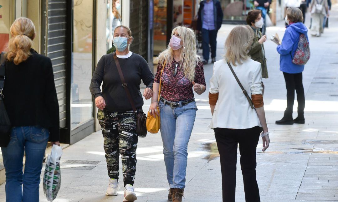 Ciudadanos pasean por una calle con mascarillas.