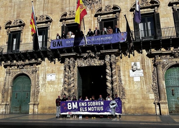 El equipo de gobierno en el balcón del palacio consistorial y la oposición progresista, con su propia pancarta, a pie de calle