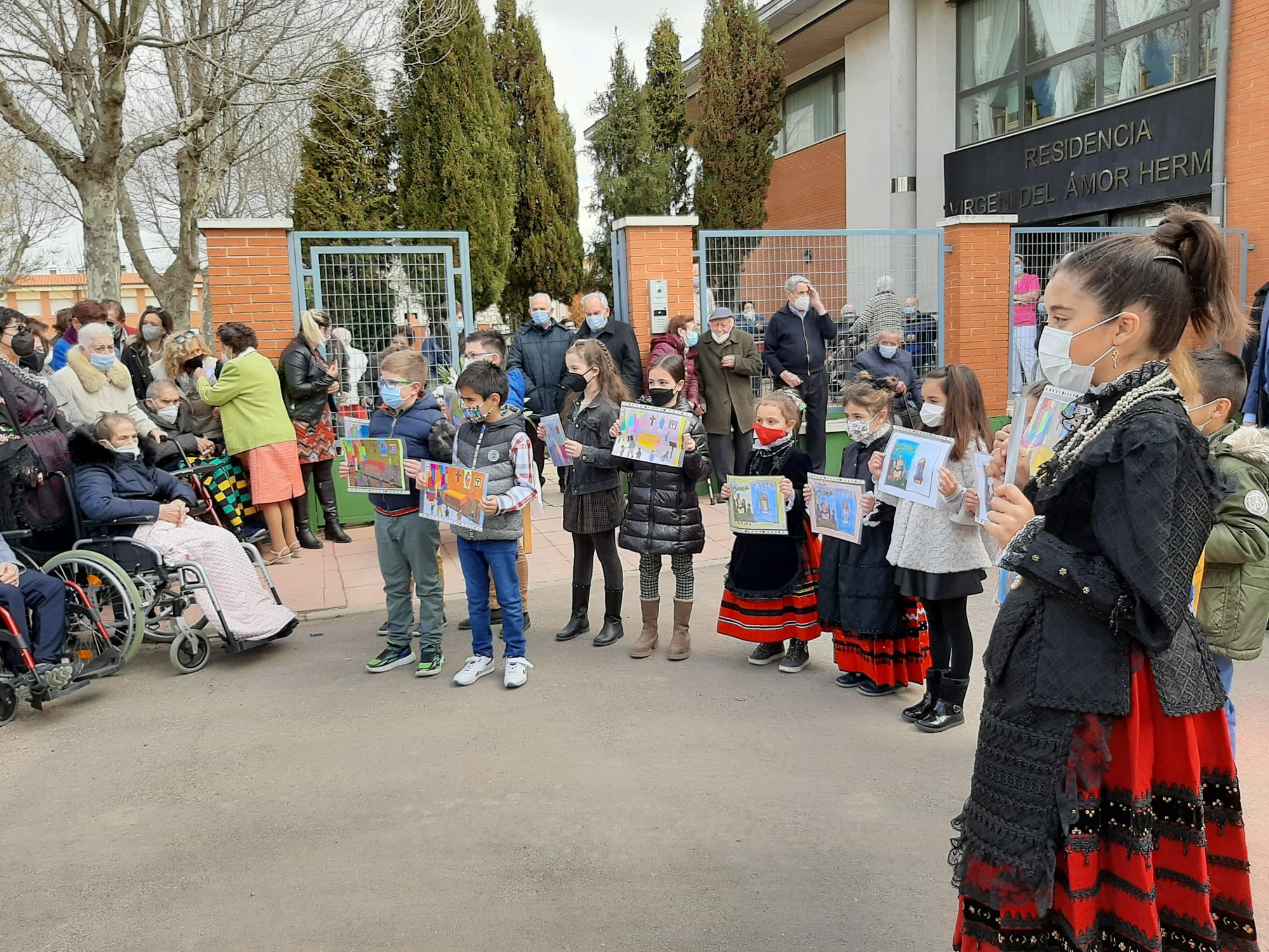 Los usuarios de la residencia de mayores de Campaspero esperan a la Virgen de El Henar y los niños de la localidad vestidos con trajes regionales le muestran sus dibujos