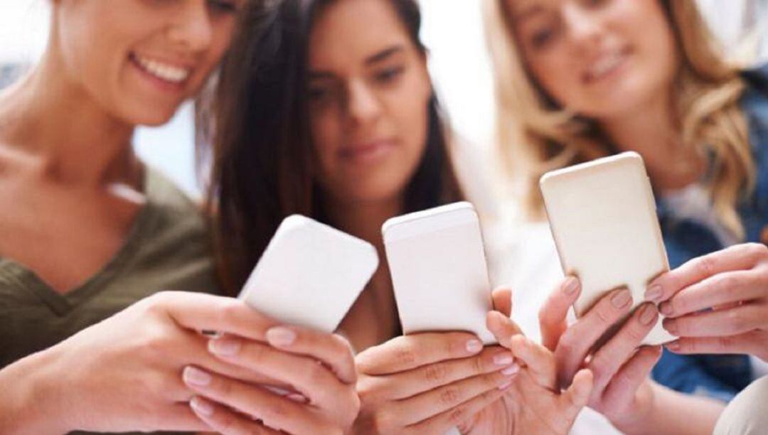 Adolescentes consultan su teléfono