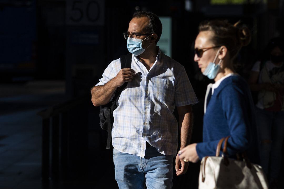 Un hombre y una mujer, con y sin mascarilla en una calle