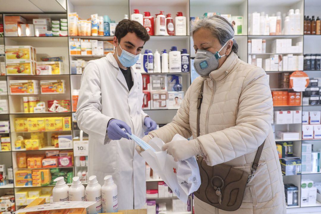 Un farmacéutico da una mascarilla a una mujer durante el reparto de mascarillas contra el Covid-19