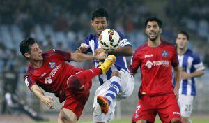 El delantero mexicano de la Real Sociedad, Carlos Vela (c), intenta superar la entrada del defensa del Getafe, Sergío Escudero (i), durante el encuentro correspondiente a la octava jornada de primera división, que han disputado esta noche en el estadio de Anoeta.