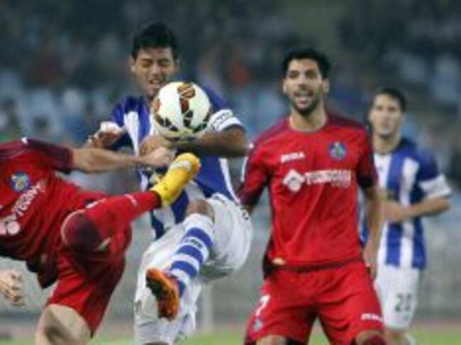 El delantero mexicano de la Real Sociedad, Carlos Vela (c), intenta superar la entrada del defensa del Getafe, Sergío Escudero (i), durante el encuentro correspondiente a la octava jornada de primera división, que han disputado esta noche en el estadio de Anoeta.