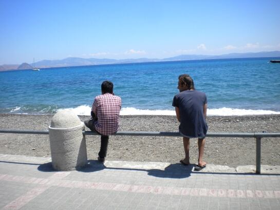 Dos refugiados en el paseo marítimo mirando hacia Turquia