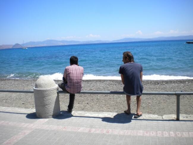 Dos refugiados en el paseo marítimo mirando hacia Turquia