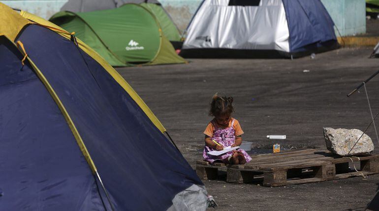 Una niña aprende a escribir en el campamento montado en el puerto del Pireo (Grecia)