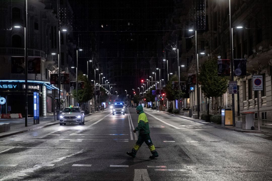 Un operario de los servicios de limpieza cruza la Gran Vía en la primera jornada de toque de queda en Madrid.