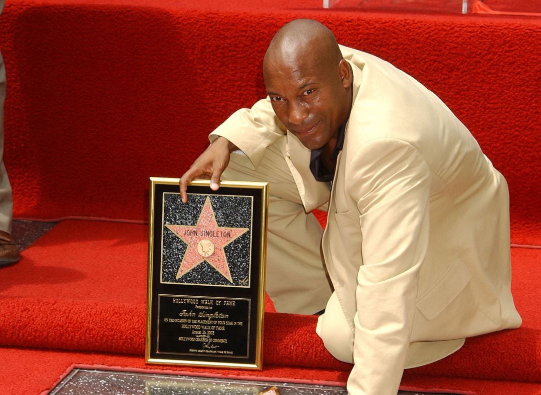 John Singleton posa con su estrella en el Paseo de la Fama