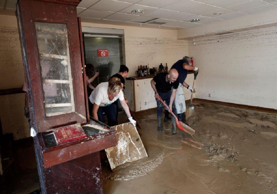 Voluntarios limpian el interior del Restaurante Brasas anegado por el agua y el barro en Tafalla