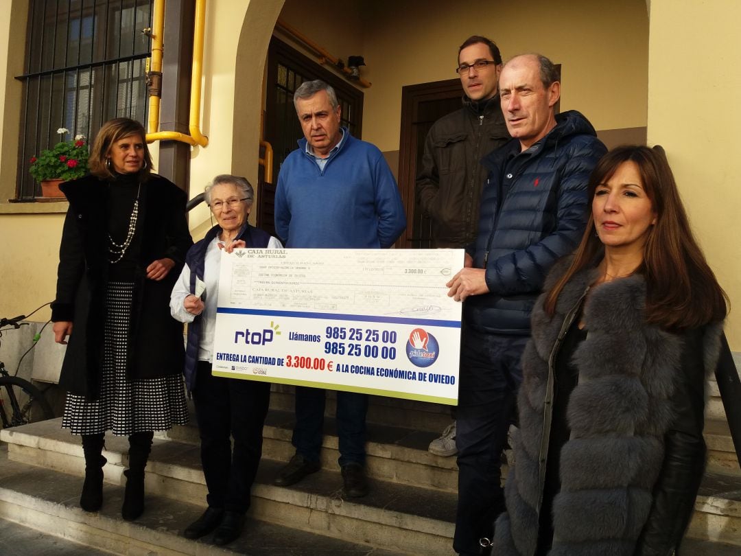 El presidente de la cooperativa Radio Taxi Oviedo y la directora de la Cocina Económica sostienen la reproduccion del cheque donado por los taxistas de la capital