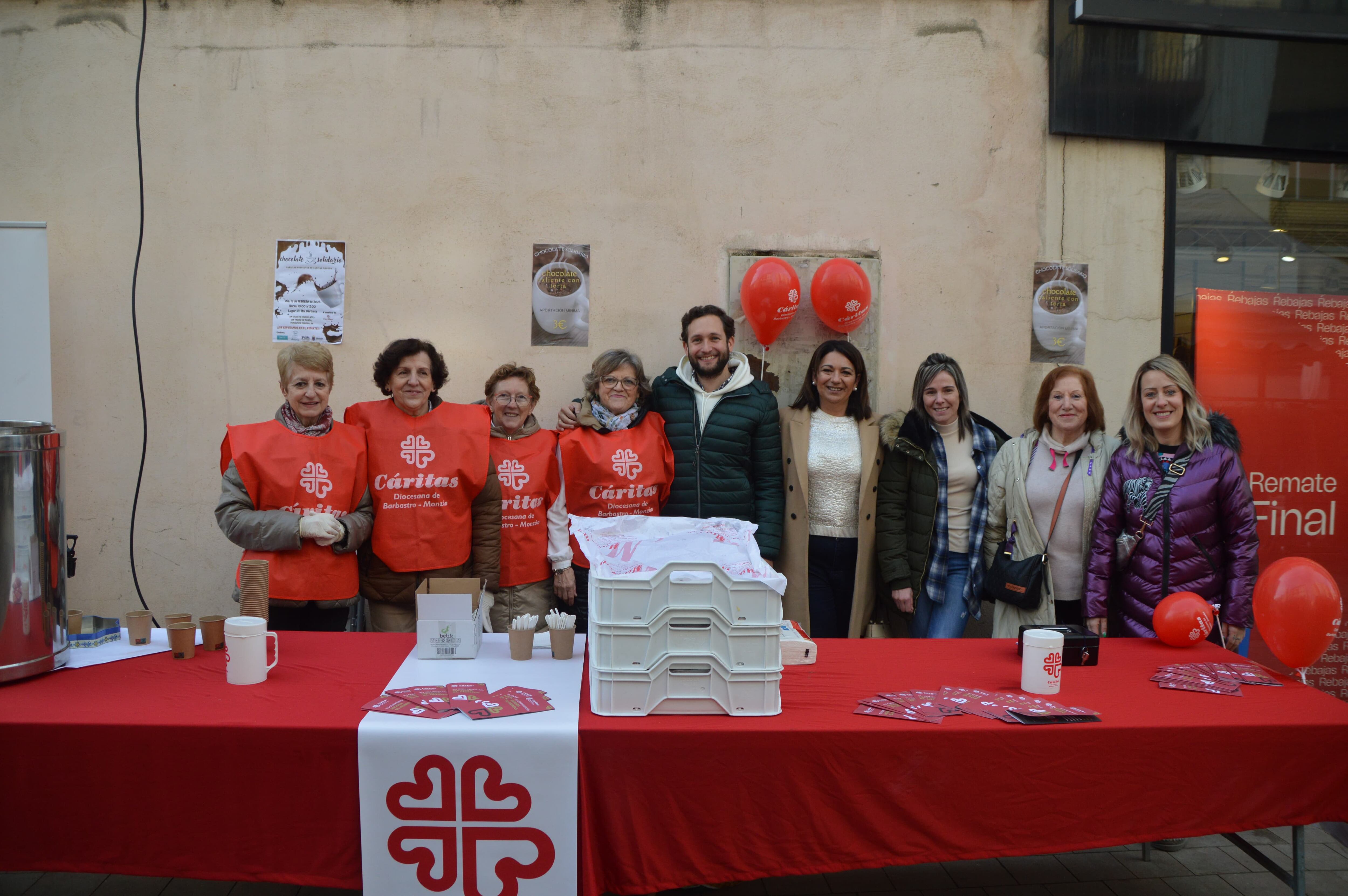 El alcalde de Monzón, Isaac Claver, junto a las representantes de Cáritas, que ofrecían una chocolatada en el Remate de Invierno