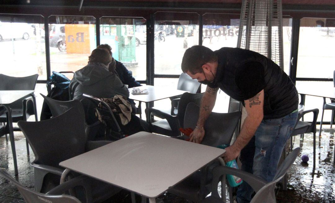 Un hostelero desinfecta una terraza de un bar