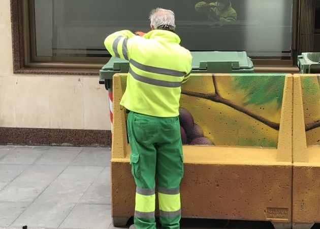 Uno de los operarios retirando las tapas de los contenedores de basura de Valdepeñas