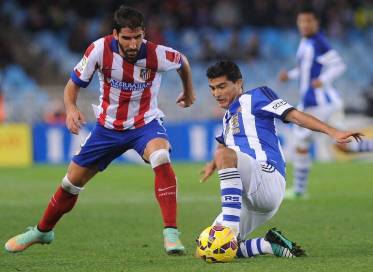 Atletico Madrid&#039;s midfielder Raul Garcia (C) vies with Real Sociedad&#039;s Uruguayan forward Chori Castro (R) during the Spanish league football match Real Sociedad vs Atletico de Madrid at the Anoeta stadium in San Sebastian on November 9, 2014.   AFP PHOTO/ RAFA RIVAS