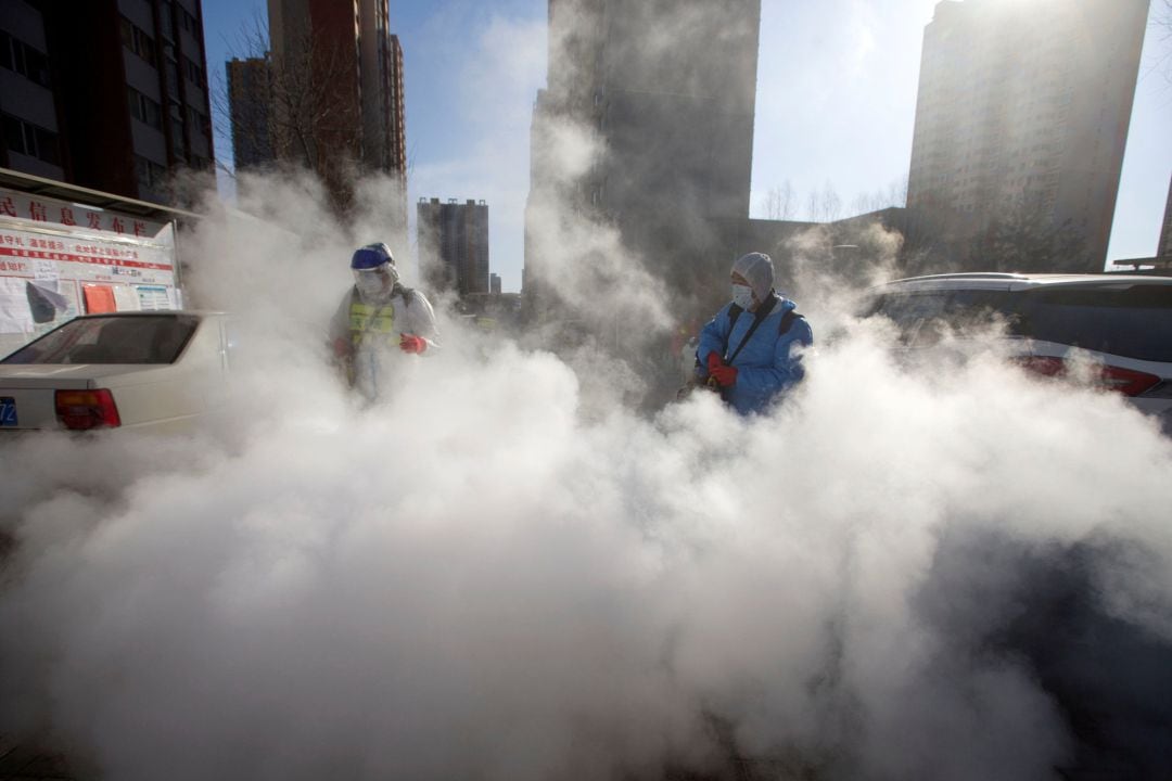 Los trabajadores usan trajes protectores y mascarillas desinfectan un complejo residencial