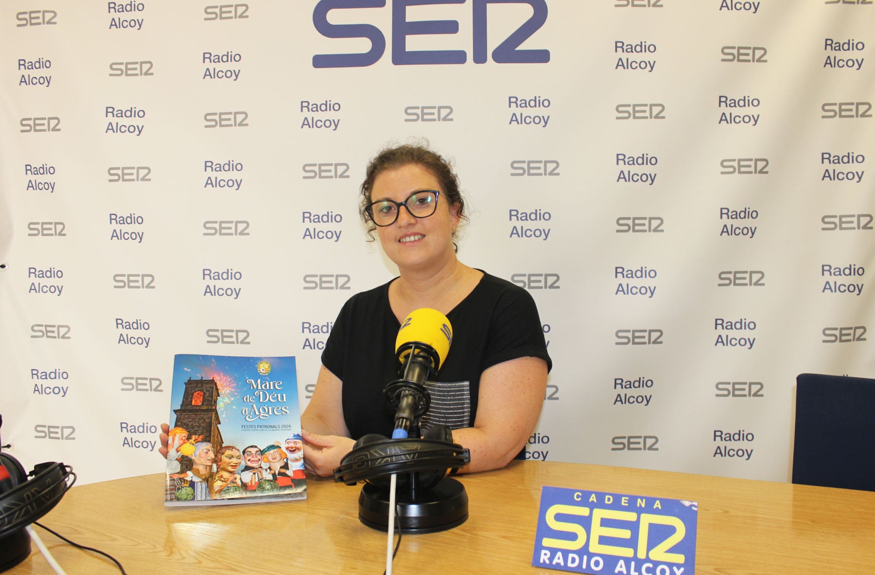 María García, alcaldessa d'Agres, amb un exemplar del programa de festes, en l'estudi central de Radio Alcoy